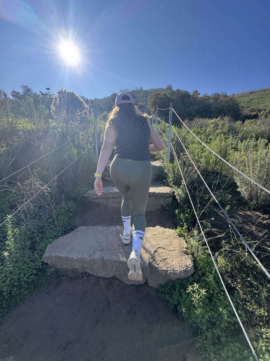 Jenn hiking up a sunlit trail