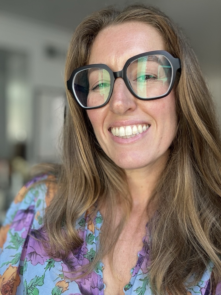 Jenn Smukler smiling, in glasses and a floral top